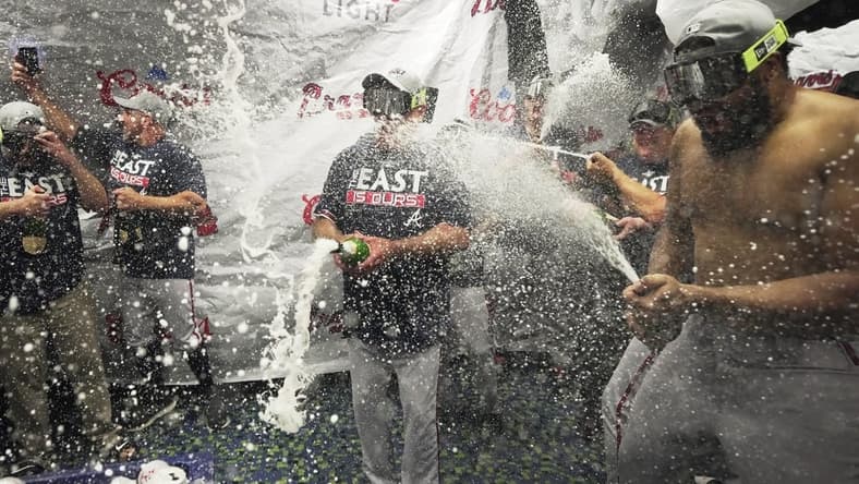 Oct 4, 2022; Miami, Florida, USA; Atlanta Braves manager Brian Snitker, center, and pitcher Kenley Jansen, right, celebrate winning the NL East division with a 2-1 victory over the Miami Marlins at loanDepot Park. Mandatory Credit: Jim Rassol-USA TODAY Sports