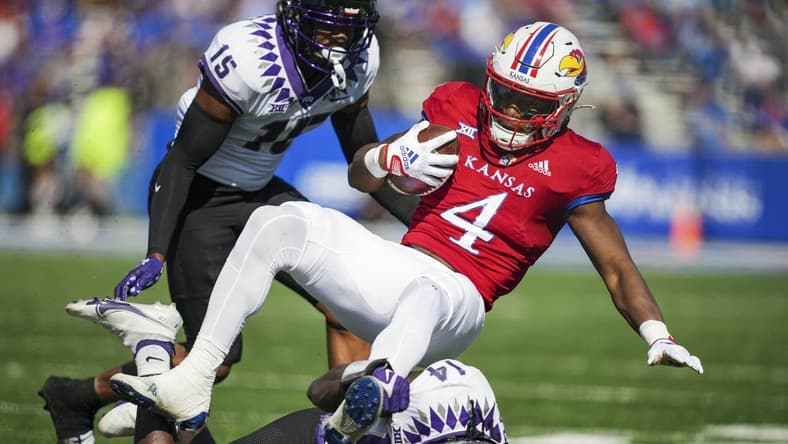 Oct 8, 2022; Lawrence, Kansas, USA; Kansas Jayhawks running back Devin Neal (4) is tackled by TCU Horned Frogs safety Abraham Camara (14) and safety Josh Foster (15) during the first half at David Booth Kansas Memorial Stadium. Mandatory Credit: Jay Biggerstaff-USA TODAY Sports