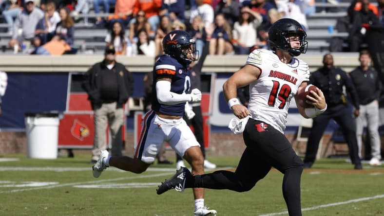 Oct 8, 2022; Charlottesville, Virginia, USA; Louisville Cardinals quarterback Brock Domann (19) scores a touchdown as Virginia Cavaliers safety Antonio Clary (0) chases during the second quarter at Scott Stadium. Mandatory Credit: Geoff Burke-USA TODAY Sports