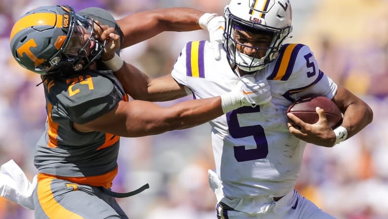 Oct 8, 2022; Baton Rouge, Louisiana, USA;  LSU Tigers quarterback Jayden Daniels (5) stiff arms Tennessee Volunteers linebacker Aaron Beasley (24) as he tries to tackle him during the second half at Tiger Stadium. Mandatory Credit: Stephen Lew-USA TODAY Sports