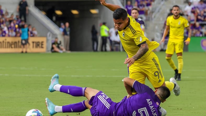 Oct 9, 2022; Orlando, Florida, USA; Orlando City midfielder Cesar Araujo (5) takes a fall in front of Columbus Crew midfielder Kevin Molino (9) during the first half at Exploria Stadium. Mandatory Credit: Mike Watters-USA TODAY Sports