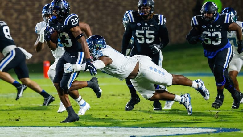 Oct 15, 2022; Durham, North Carolina, USA; Duke Blue Devils running back Terry Moore (23) runs with the ball while North Carolina Tar Heels defensive lineman Jahvaree Ritzie (5) tries to tackle him during the first half at Wallace Wade Stadium. Mandatory Credit: Jaylynn Nash-USA TODAY Sports