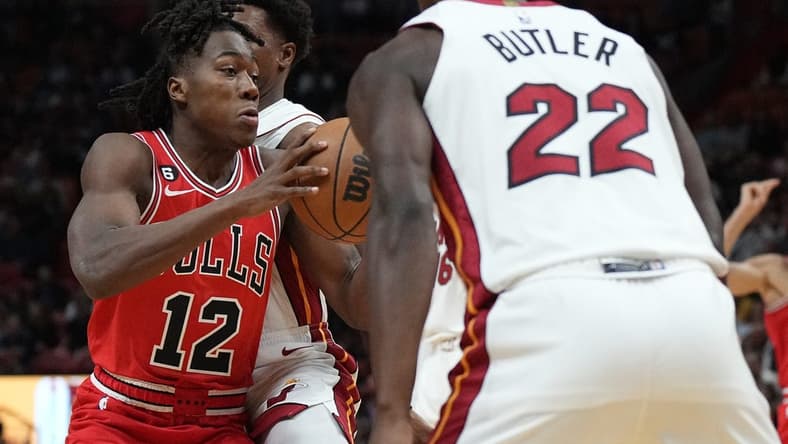 Oct 19, 2022; Miami, Florida, USA; Chicago Bulls guard Ayo Dosunmu (12) splits the defense of Miami Heat guard Kyle Lowry (7) and forward Jimmy Butler (22) in the first half at FTX Arena. Mandatory Credit: Jim Rassol-USA TODAY Sports