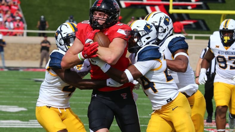 Oct 22, 2022; Lubbock, Texas, USA; Texas Tech Red Raiders tight end Mason Tharp (80) is tackled by West Virginia Mountaineers defensive safety Marcis Floyd (24), defensive corner back Rashad Ajayi (4) and defensive linebacker Jasir Cox (7) in the first half at Jones AT&T Stadium and Cody Campbell Field. Mandatory Credit: Michael C. Johnson-USA TODAY Sports