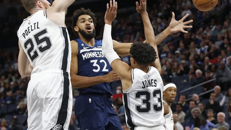 Oct 26, 2022; Minneapolis, Minnesota, USA; Minnesota Timberwolves center Karl-Anthony Towns (32) passes the ball away from the defense of San Antonio Spurs center Jakob Poeltl (25) and guard Tre Jones (33) in the fourth quarter at Target Center. Mandatory Credit: Bruce Kluckhohn-USA TODAY Sports