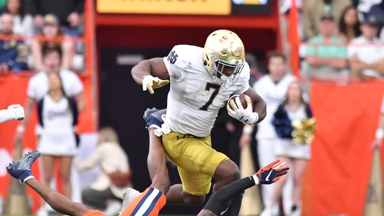 Oct 29, 2022; Syracuse, New York, USA; Notre Dame Fighting Irish running back Audric Estime (7) runs over Syracuse Orange defensive back Alijah Clark (5) in the second quarter at JMA Wireless Dome. Mandatory Credit: Mark Konezny-USA TODAY Sports