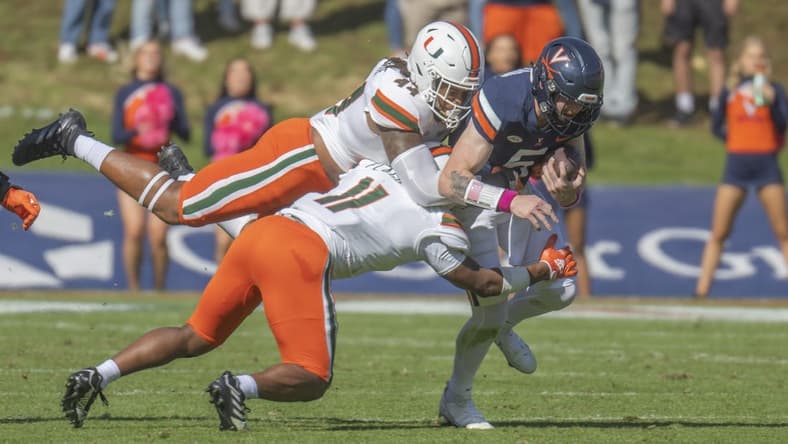 Oct 29, 2022; Charlottesville, Virginia, USA; Miami Hurricanes defensive lineman Antonio Moultrie (44) and Miami Hurricanes linebacker Corey Flagg Jr. hang on to Virginia Cavaliers quarterback Brennan Armstrong in the first half (11) at Scott Stadium. Mandatory Credit: Lee Luther Jr.-USA TODAY Sports