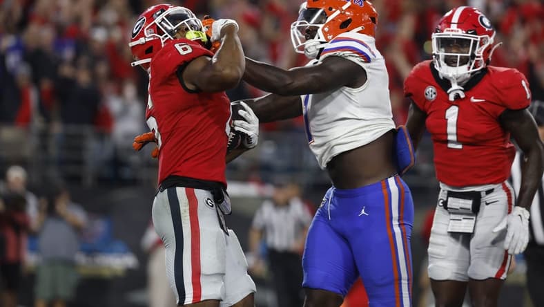 Oct 29, 2022; Jacksonville, Florida, USA; Georgia Bulldogs running back Kenny McIntosh (6) runs the ball in for a touchdown as Florida Gators linebacker Brenton Cox Jr. (1) defends during the second half at TIAA Bank Field. Mandatory Credit: Kim Klement-USA TODAY Sports