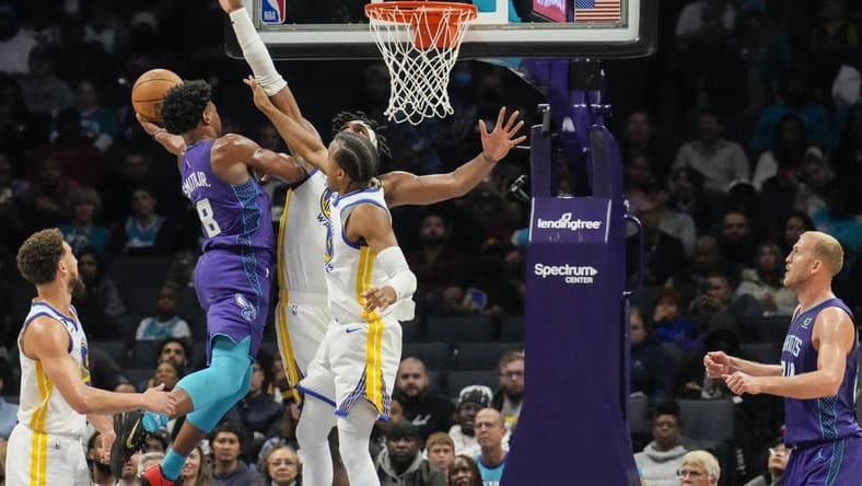 Oct 29, 2022; Charlotte, North Carolina, USA; Charlotte Hornets guard Dennis Smith Jr. (8) goes up for a shot against Golden State Warriors center Kevon Looney (5) and forward Jonathan Kuminga (00) during the second quarter at Spectrum Center. Mandatory Credit: Jim Dedmon-USA TODAY Sports