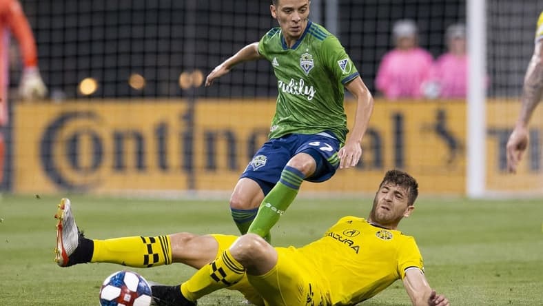 Jul 6, 2019; Columbus, OH, USA; Columbus Crew SC defender Gaston Sauro (22) tackles the ball away from Seattle Sounders forward Alfonso Ocampo-Chavez (87) at MAPFRE Stadium. Mandatory Credit: Greg Bartram-USA TODAY Sports