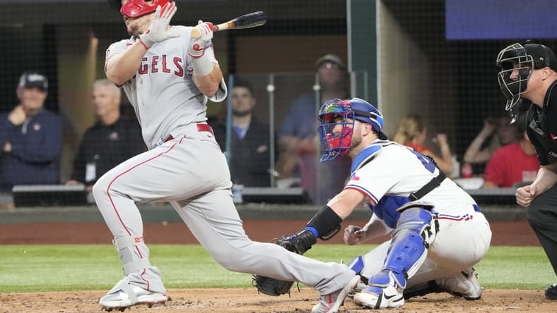 Apr 15, 2022; Arlington, Texas, USA; Los Angeles Angels center fielder Mike Trout follows through on his swing for an infield hit against the Texas Rangers during the third inning of a baseball game at Globe Life Field. Mandatory Credit: Jim Cowsert-USA TODAY Sports