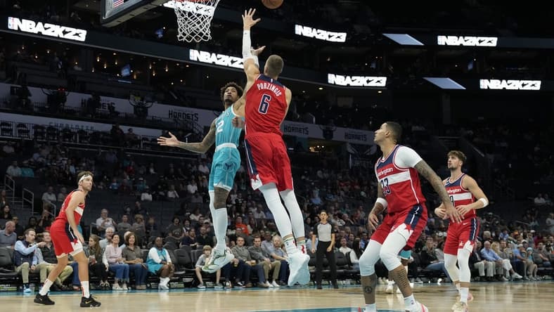 Nov 7, 2022; Charlotte, North Carolina, USA; Charlotte Hornets guard Kelly Oubre Jr. (12) shoots defended by Washington Wizards center Kristaps Porzingis (6) during the first quarter at Spectrum Center. Mandatory Credit: Jim Dedmon-USA TODAY Sports
