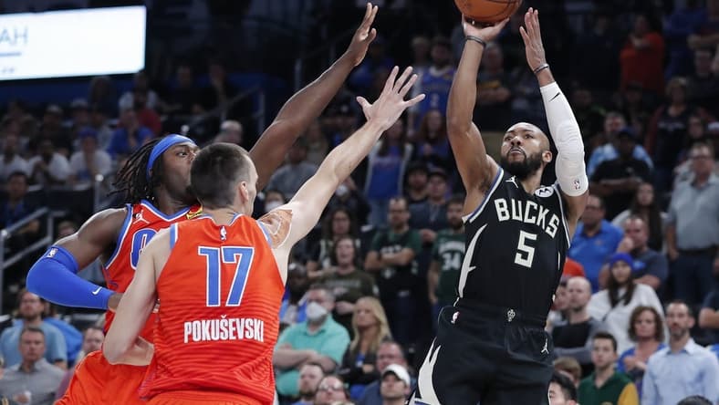 Nov 9, 2022; Oklahoma City, Oklahoma, USA; Milwaukee Bucks guard Jevon Carter (5) shoots as Oklahoma City Thunder forward Luguentz Dort (5) and forward Aleksej Pokusevski (17) defend during overtime at Paycom Center. Milwaukee won 136-132 in double overtime. Mandatory Credit: Alonzo Adams-USA TODAY Sports