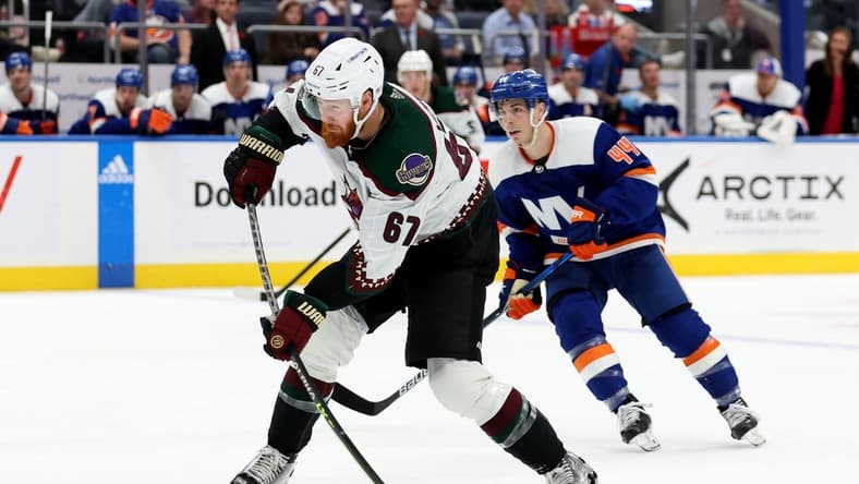 Nov 10, 2022; Elmont, New York, USA; Arizona Coyotes left wing Lawson Crouse (67) takes a shot in front of New York Islanders center Jean-Gabriel Pageau (44) during the third period at UBS Arena. Mandatory Credit: Brad Penner-USA TODAY Sports