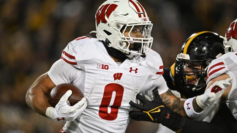 Nov 12, 2022; Iowa City, Iowa, USA; Wisconsin Badgers running back Braelon Allen (0) runs the ball as Iowa Hawkeyes defensive lineman Lukas Van Ness (91) looks to make the tackle during the fourth quarter at Kinnick Stadium. Mandatory Credit: Jeffrey Becker-USA TODAY Sports