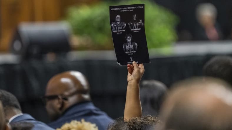 Nov 19, 2022; Charlottesville, Virginia, US; A flyer is held up during the memorial service for three slain University of Virginia football players Lavel Davis Jr., D Sean Perry and Devin Chandler at John Paul Jones Arena. Mandatory Credit: Erin Edgerton/Pool Photo-USA TODAY Sports