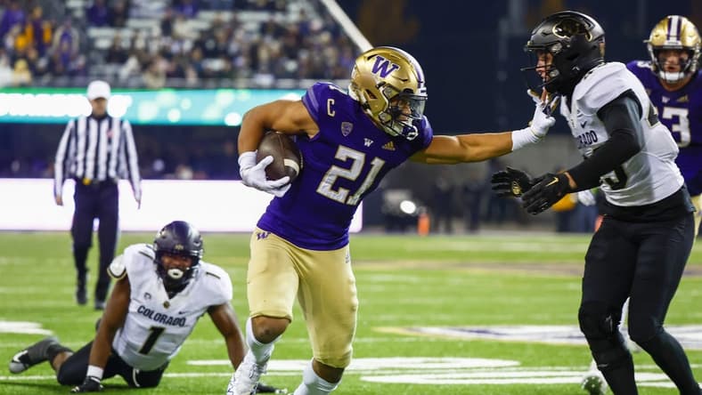 Nov 19, 2022; Seattle, Washington, USA; Washington Huskies running back Wayne Taulapapa (21) stiff arms against Colorado Buffaloes safety Trevor Woods (43) during the second quarter at Alaska Airlines Field at Husky Stadium. Mandatory Credit: Joe Nicholson-USA TODAY Sports