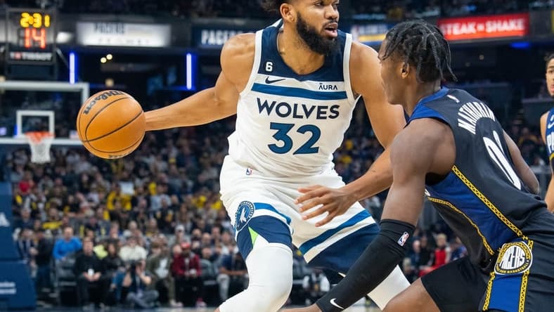 Nov 23, 2022; Indianapolis, Indiana, USA; Minnesota Timberwolves center Karl-Anthony Towns (32) dribbles the ball while Indiana Pacers guard Bennedict Mathurin (00) defends in the first quarter at Gainbridge Fieldhouse. Mandatory Credit: Trevor Ruszkowski-USA TODAY Sports