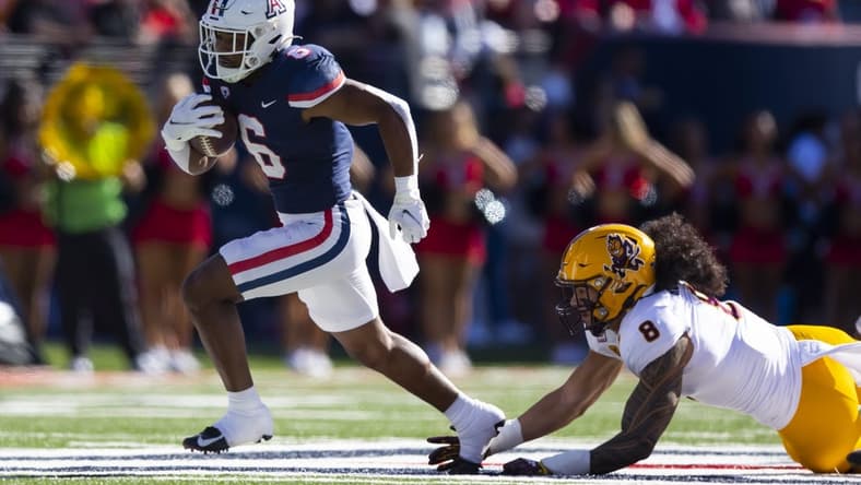 Nov 25, 2022; Tucson, Arizona, USA; Arizona Wildcats running back Michael Wiley (6) runs for a touchdown against diving Arizona State Sun Devils linebacker Merlin Robertson (8) in the first half of the Territorial Cup at Arizona Stadium. Mandatory Credit: Mark J. Rebilas-USA TODAY Sports