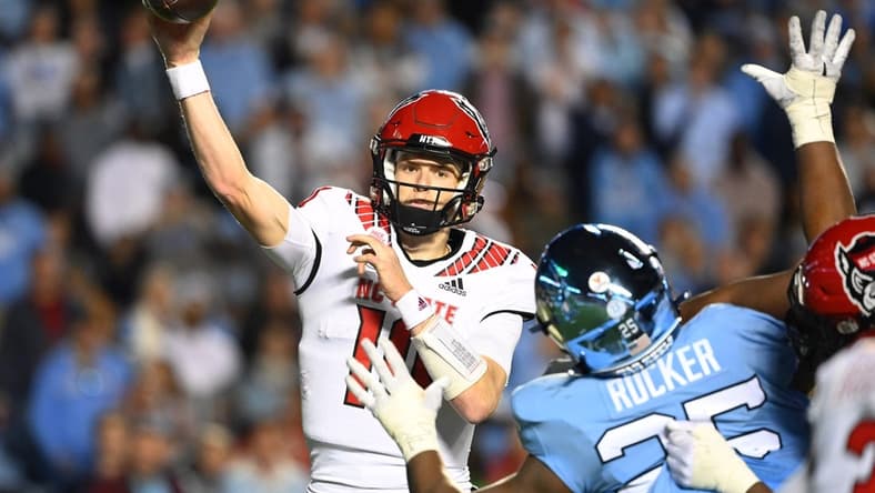 Nov 25, 2022; Chapel Hill, North Carolina, USA; North Carolina State Wolfpack quarterback Ben Finley (10) passes the ball as North Carolina Tar Heels defensive lineman Kaimon Rucker (25) defends in the fourth quarter at Kenan Memorial Stadium. Mandatory Credit: Bob Donnan-USA TODAY Sports