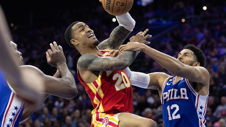 Nov 28, 2022; Philadelphia, Pennsylvania, USA; Atlanta Hawks forward John Collins (20) is fouled while driving for a shot between Philadelphia 76ers forward Tobias Harris (12) and center Joel Embiid (21) during the second quarter at Wells Fargo Center. Mandatory Credit: Bill Streicher-USA TODAY Sports