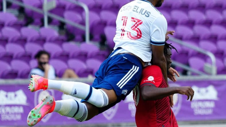 Apr 24, 2021; Orlando, Florida, USA; Vancouver Whitecaps defender Derek Cornelius (13) and Toronto FC forward Ayo Akinola (20) fight for the ball during the second half at Orlando City Stadium. Mandatory Credit: Douglas DeFelice-USA TODAY Sports
