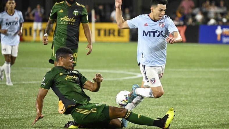 Aug 6, 2022; Portland, Oregon, USA; Portland Timbers defender Zac McGraw (18) slide tackles FC Dallas forward Alan Velasco (20) during the second half at Providence Park. The game ended tied 1-1. Mandatory Credit: Troy Wayrynen-USA TODAY Sports