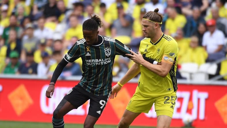 Sep 10, 2022; Nashville, Tennessee, USA; Los Angeles Galaxy forward Kevin Cabral (9) works against Nashville SC defender Walker Zimmerman (25) during the first half at Geodis Park. Mandatory Credit: Christopher Hanewinckel-USA TODAY Sports