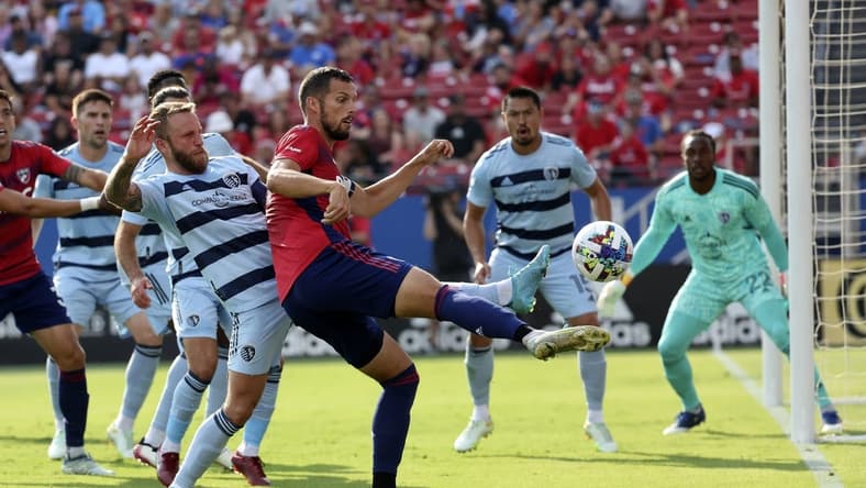 Oct 9, 2022; Frisco, Texas, USA;  FC Dallas defender Matt Hedges (24) shoots on goal as Sporting Kansas City forward Johnny Russell (7) defends during the first half at Toyota Stadium. Mandatory Credit: Kevin Jairaj-USA TODAY Sports