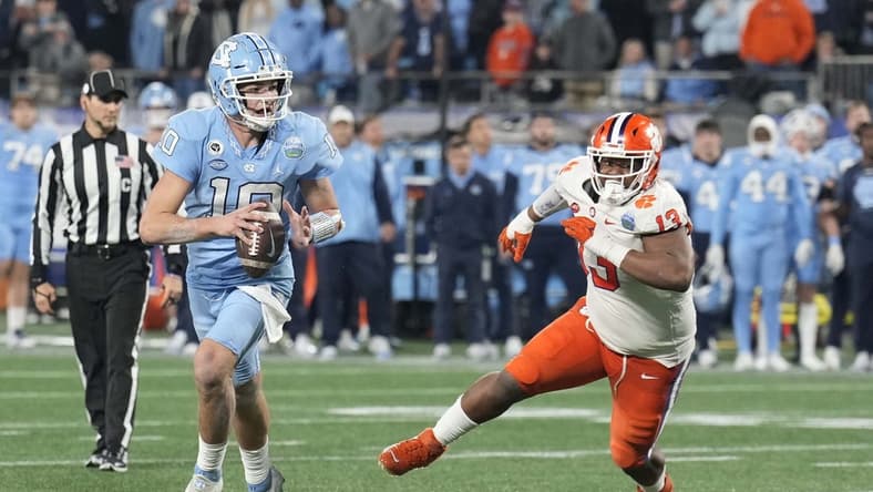 Dec 3, 2022; Charlotte, North Carolina, USA; North Carolina Tar Heels quarterback Drake Maye (10) scrambles past Clemson Tigers defensive tackle Tyler Davis (13) during the third quarter of the ACC Championship game at Bank of America Stadium. Mandatory Credit: Jim Dedmon-USA TODAY Sports