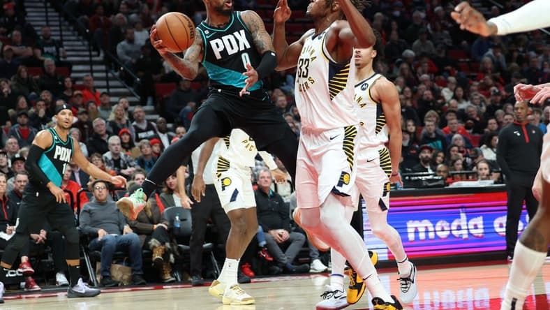 Dec 4, 2022; Portland, Oregon, USA; Portland Trail Blazers guard Damian Lillard (0) passes the ball around Indiana Pacers center Myles Turner (33) in the first half at Moda Center. Mandatory Credit: Jaime Valdez-USA TODAY Sports