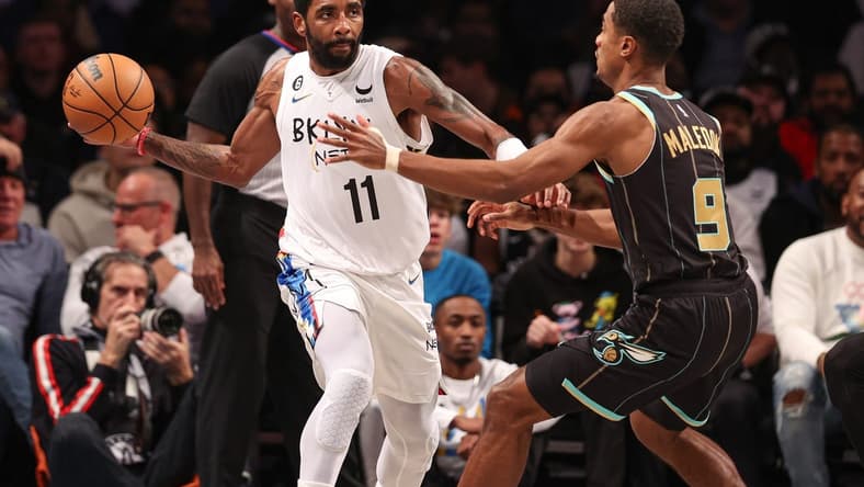 Dec 7, 2022; Brooklyn, New York, USA; Brooklyn Nets guard Kyrie Irving (11) passes the ball during the first half as Charlotte Hornets guard Theo Maledon (9) defends at Barclays Center. Mandatory Credit: Vincent Carchietta-USA TODAY Sports