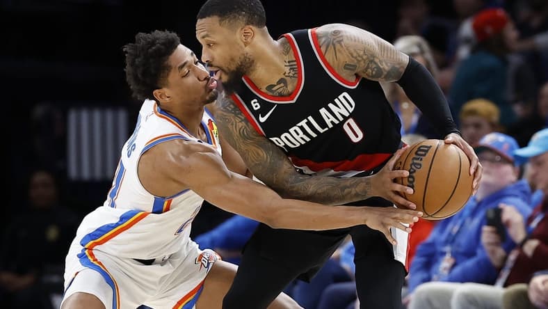 Dec 19, 2022; Oklahoma City, Oklahoma, USA; Portland Trail Blazers guard Damian Lillard (0) is defended by Oklahoma City Thunder guard Aaron Wiggins (21) on a drive during the second half at Paycom Center. Oklahoma City won 123-121. Mandatory Credit: Alonzo Adams-USA TODAY Sports