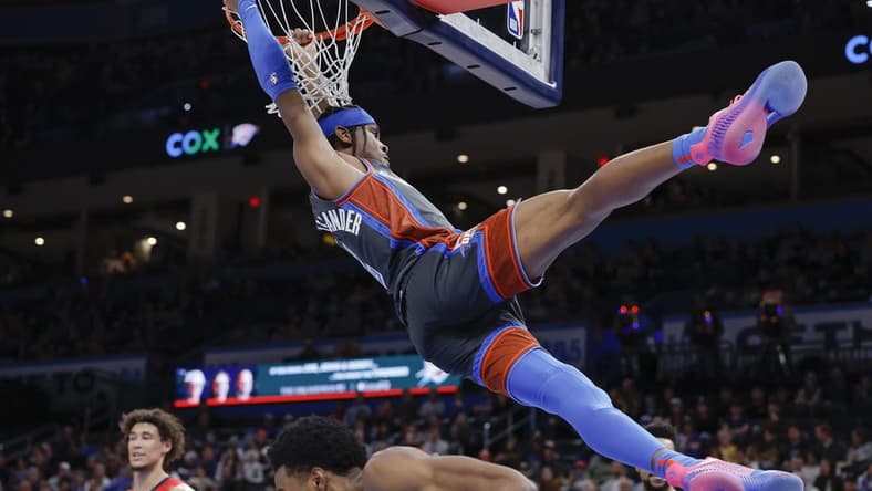 Dec 23, 2022; Oklahoma City, Oklahoma, USA; Oklahoma City Thunder guard Shai Gilgeous-Alexander (2) hangs on the basket after dunking against the New Orleans Pelicans during the second quarter at Paycom Center. Mandatory Credit: Alonzo Adams-USA TODAY Sports
