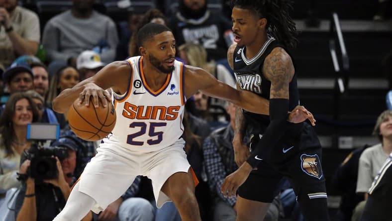 Dec 27, 2022; Memphis, Tennessee, USA; Phoenix Suns forward Mikal Bridges (25) dribbles to the basket as Memphis Grizzlies guard Ja Morant (12) defends during the first half at FedExForum. Mandatory Credit: Petre Thomas-USA TODAY Sports