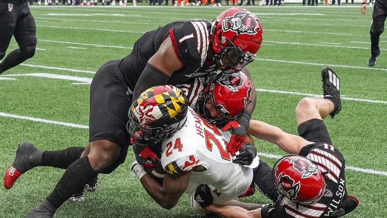 Dec 30, 2022; Charlotte, NC, USA; North Carolina State Wolfpack linebacker Isaiah Moore (1) and linebacker Payton Wilson (11) stop Maryland Terrapins running back Roman Hemby (24) on fourth down during the first half in the 2022 Duke's Mayo Bowl at Bank of America Stadium. Mandatory Credit: Jim Dedmon-USA TODAY Sports
