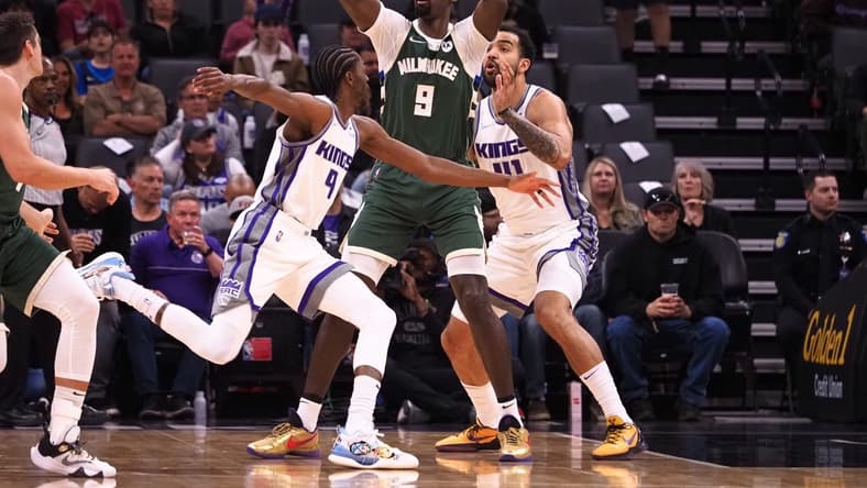 Mar 16, 2022; Sacramento, California, USA; Milwaukee Bucks forward Bobby Portis Jr. (9) controls the ball between Sacramento Kings guard Justin Holiday (9) and forward Trey Lyles (41) during the first quarter at Golden 1 Center. Mandatory Credit: Kelley L Cox-USA TODAY Sports