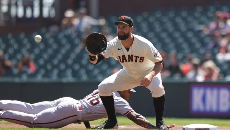 Aug 18, 2022; San Francisco, California, USA; San Francisco Giants first baseman Brandon Belt (9) catches the ball as Arizona Diamondbacks left fielder Stone Garrett (46) dives back to first base during the first inning against the San Francisco Giants at Oracle Park. Mandatory Credit: Sergio Estrada-USA TODAY Sports