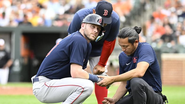 Sep 10, 2022; Baltimore, Maryland, USA; Boston Red Sox second baseman Trevor Story (10) is checked by the team trainer after being hit by a pitch during the first inning against the Baltimore Orioles at Oriole Park at Camden Yards. Mandatory Credit: James A. Pittman-USA TODAY Sports