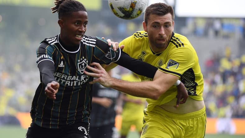 Sep 10, 2022; Nashville, Tennessee, USA; Los Angeles Galaxy forward Kevin Cabral (9) and Nashville SC defender Dave Romney (4) battle for a loose ball during the first half at Geodis Park. Mandatory Credit: Christopher Hanewinckel-USA TODAY Sports