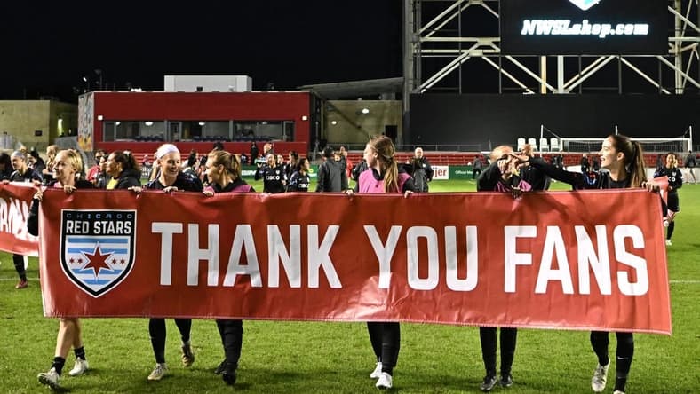 Oct 2, 2022; Bridgeview, Illinois, USA; Chicago Red Stars teammates hold up a sign to thank their fans after the game against Angel City FC at SeatGeek Stadium. Mandatory Credit: Daniel Bartel-USA TODAY Sports