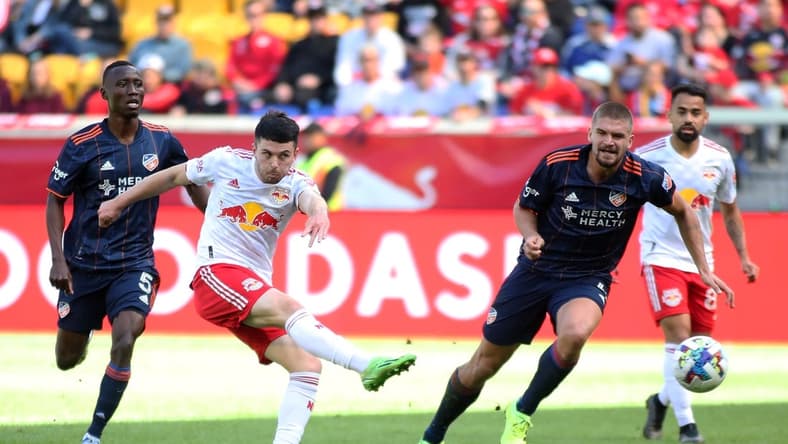 Oct 15, 2022; Harrison, New Jersey, USA; New York Red Bulls midfielder Lewis Morgan (10) kicks the ball against FC Cincinnati midfielder Obinna Nwobodo (5) and defender Nick Hagglund (4) during the first half at Red Bull Arena. Mandatory Credit: Wendell Cruz-USA TODAY Sports