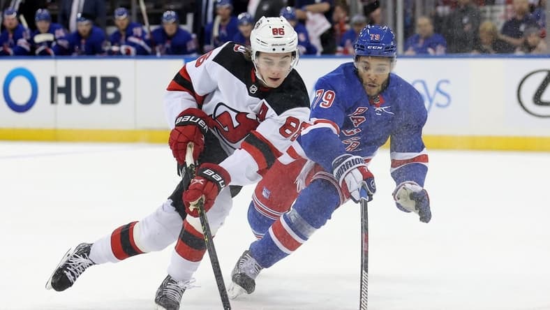 Dec 12, 2022; New York, New York, USA; New York Rangers defenseman K'Andre Miller (79) knocks the puck away from New Jersey Devils center Jack Hughes (86) during the first period at Madison Square Garden. Mandatory Credit: Brad Penner-USA TODAY Sports