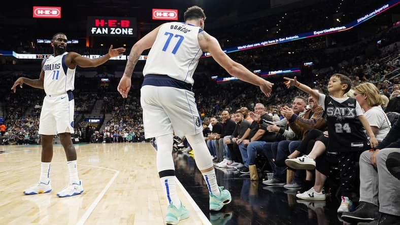 Dec 31, 2022; San Antonio, Texas, USA; Dallas Mavericks guard Luka Doncic (77) reaches for a fan as guard Tim Hardaway Jr. waits during the second half against the San Antonio Spurs at AT&T Center. Mandatory Credit: Scott Wachter-USA TODAY Sports
