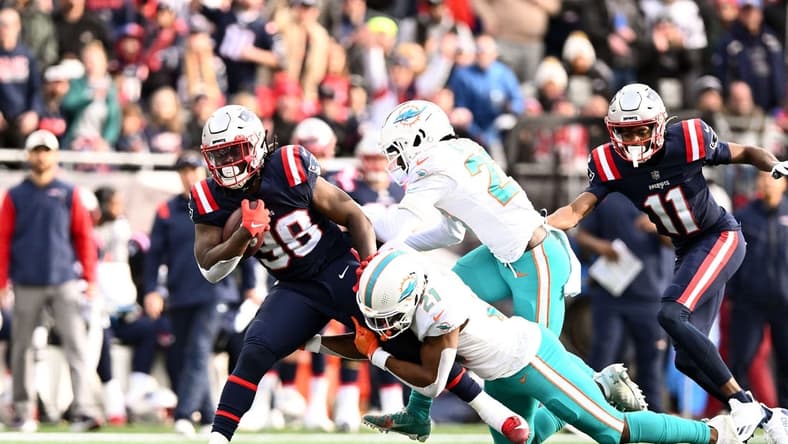 Jan 1, 2023; Foxborough, Massachusetts, USA; Miami Dolphins safety Eric Rowe (21) takles New England Patriots running back Rhamondre Stevenson (38) during the first half at Gillette Stadium. Mandatory Credit: Brian Fluharty-USA TODAY Sports