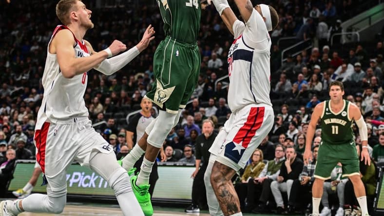 Jan 3, 2023; Milwaukee, Wisconsin, USA; Milwaukee Bucks forward Giannis Antetokounmpo (34) takes a shot between Washington Wizards forward Kristaps Porzingis (6) and center Daniel Gafford (21) in the fourth quarter at Fiserv Forum. Mandatory Credit: Benny Sieu-USA TODAY Sports