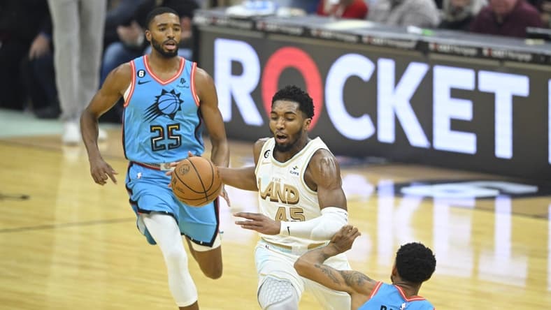 Jan 4, 2023; Cleveland, Ohio, USA; Cleveland Cavaliers guard Donovan Mitchell (45) dribbles between Phoenix Suns forward Mikal Bridges (25) and guard Cameron Payne (15) in the first quarter at Rocket Mortgage FieldHouse. Mandatory Credit: David Richard-USA TODAY Sports