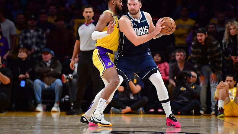 Jan 12, 2023; Los Angeles, California, USA; Dallas Mavericks guard Luka Doncic (77) moves the ball against Los Angeles Lakers forward Troy Brown Jr. (7) during overtime at Crypto.com Arena. Mandatory Credit: Gary A. Vasquez-USA TODAY Sports