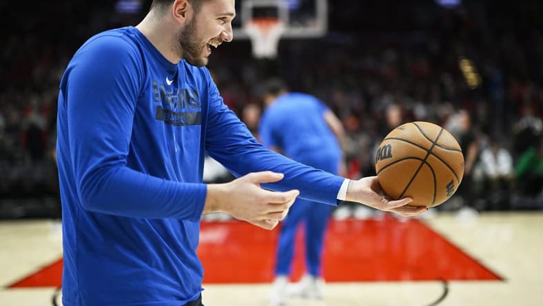 Jan 14, 2023; Portland, Oregon, USA; Dallas Mavericks guard Luka Doncic (77) playfully hands the ball to an assistant coach before a game against the Portland Trail Blazers at Moda Center. Mandatory Credit: Troy Wayrynen-USA TODAY Sports