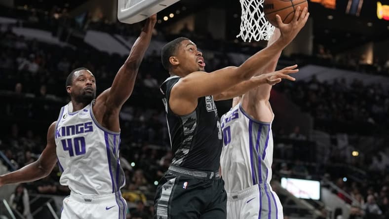 Jan 15, 2023; San Antonio, Texas, USA; San Antonio Spurs forward Keldon Johnson (3) shoots in front of Sacramento Kings forwards Harrison Barnes (40) and Domantas Sabonis (10) in the first half at the AT&T Center. Mandatory Credit: Daniel Dunn-USA TODAY Sports